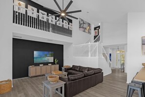 A spacious living area with a large sectional sofa, a flat-screen TV, and a ceiling fan.