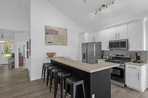 A modern kitchen with white cabinets, stainless steel appliances, and a long island with bar stools.