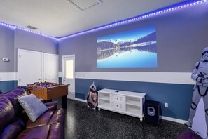 A room with a foosball table, Star Wars decorations, a large window, and a white cabinet.