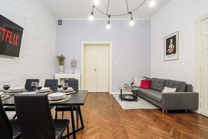 A modern living space with a dining area, a grey sofa, and a fireplace. - Apartment near Moniuszko Park (Łódź)