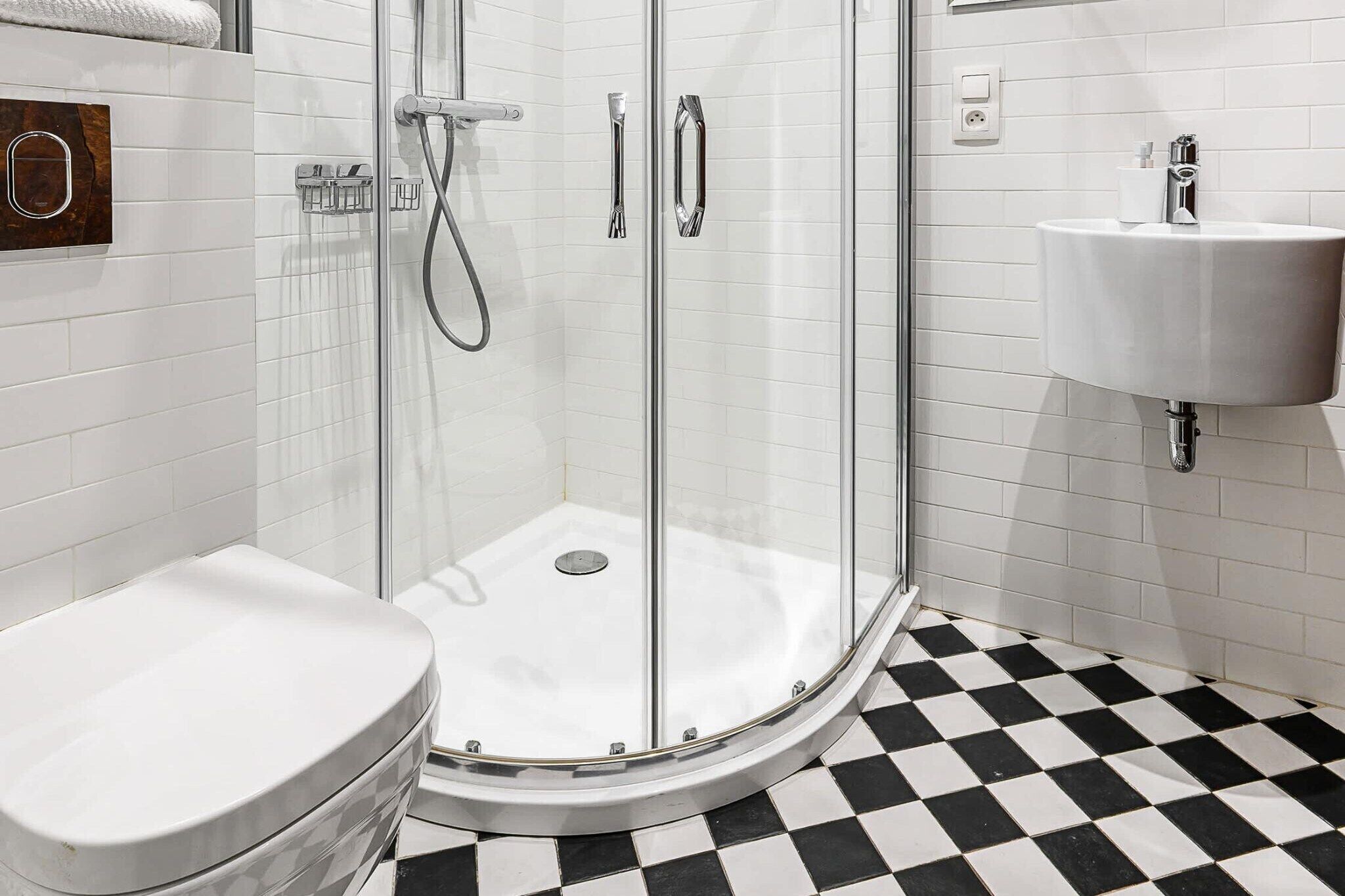A modern bathroom with a glass-enclosed shower, a white toilet, and a sink with a mirror.