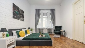 Ein modernes Schlafzimmer mit einem Bett, einem Nachttisch, einem Sessel und einem Fernseher.