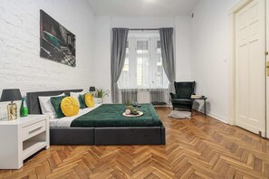 Ein modernes Schlafzimmer mit einem Bett, einem Nachttisch, einem Sessel und einem Fernseher.