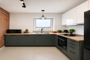 Eine moderne Küche mit einem großen Fenster, einem eingebauten Backofen und einer Mikrowelle.