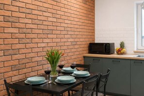 A dining area with a brick wall, a table set for four, and a microwave on the counter. - Modern Family Getaway in Łódź  CIty (Łódź)