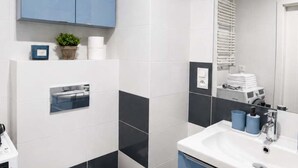 A modern bathroom with a white sink, blue towels, and a mirror. - Modern Romantic CIty Getaway (Łódź)