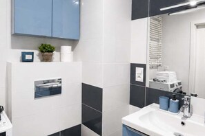 Ein modernes Badezimmer mit einem weißen Waschbecken, blauen Handtüchern und einem Spiegel.