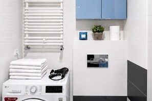 A laundry area with stacked towels, a washing machine, and a dryer. - Modern Family Getaway in Łódź  CIty (Łódź)