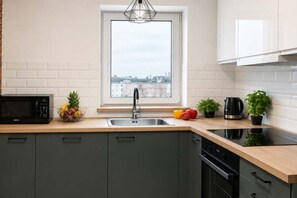 A modern kitchen with a window, a sink, a microwave, and a stove. - Modern Family Getaway in Łódź  CIty (Łódź)