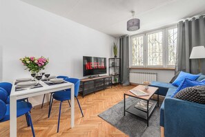 A modern living room with a dining area, a flat-screen TV, and a large window with curtains. - Stay in Warsaw Center (Warszawa)