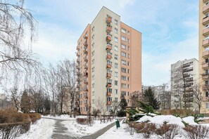 A multi-story residential building with balconies, a snow-covered path, and leafless trees. - Stay in Warsaw Center (Warszawa)