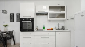 Una cucina moderna con mobili bianchi, forno nero, lavello e frigorifero.