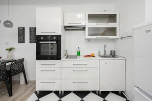 Eine moderne Küche mit weißen Schränken, einem schwarzen Backofen, einer Spüle und einem Kühlschrank.