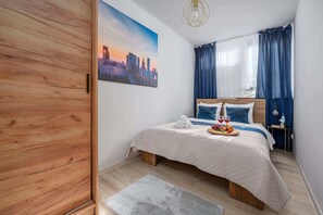 Ein Schlafzimmer mit einem Bett, einem Stadtbild, einem Nachttisch und einem Fenster mit Vorhängen.