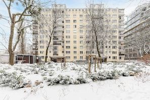 A multi-story residential building with balconies, surrounded by snow-covered bushes and trees. - House in Plourin near Sandy Beaches (Warszawa 2)
