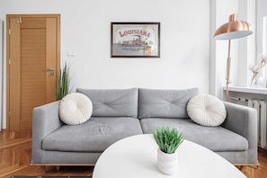 A modern living room with a grey sofa, two decorative pillows, a white coffee table, a potted plant, and a framed picture on the wall. - House in Plourin near Sandy Beaches (Warszawa 2)