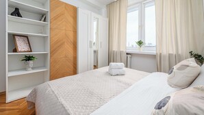 Ein Hotelzimmer mit Bett, Schrank, einem Fenster mit Vorhängen und einer Zimmerpflanze.