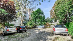 A gravel driveway with parked cars and a building in the background. - Lush Flat in Lodz Center (Łódź)
