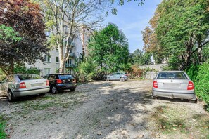 Ein gepflegter Schotterweg mit geparkten Autos und einem Gebäude im Hintergrund.