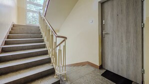 A staircase with a handrail leading to a door with a wooden finish. - Lush Flat in Lodz Center (Łódź)