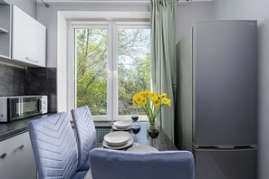 Una cocina moderna con comedor, refrigerador y ventana con vista a árboles.