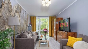 A modern living room with a sofa, a coffee table, a TV, and a bookshelf. - Lush Flat in Lodz Center (Łódź)