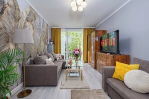Ein modernes Wohnzimmer mit einer Couch, einem Couchtisch, einem Fernseher und einem Bücherregal.