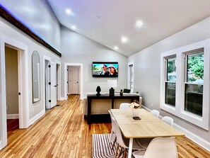Ein modernes Interieur mit Essbereich, einer Küche und einem an der Wand befestigten Fernseher.