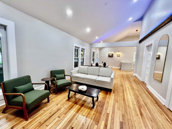 A spacious living area with a wooden floor, a sofa, two armchairs, and a coffee table. - The Carter Home 3Beds-2Ba-2Tvs minutes way to Lakepoint Sports (Cartersville)