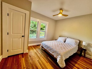 Ein Schlafzimmer mit Bett, Deckenventilator, Fenster und Tür.