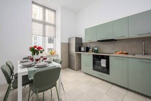 Eine moderne Küche mit Essbereich, ausgestattet mit einem Tisch für zwei Personen, einem Kühlschrank, einem Backofen und einer Mikrowelle.