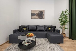 A modern living room with a sectional sofa, a glass coffee table, and a potted plant. - 8-Person Holiday Apartment in Łódź (Łódź)
