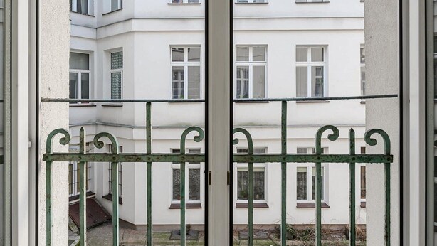 A view through a metal gate of a building with multiple windows and a visible staircase. - Holiday Home in Porspoder near Plage du Bourg (Łódź)