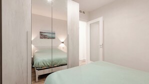 Una camera da letto con un letto, un comodino, uno specchio e una lampada a parete.