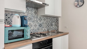 Una cucina compatta con microonde, bollitore e fornello.