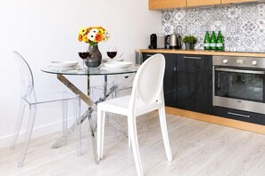 Eine moderne Küche mit einem Glastisch, weißen Stühlen und einer Vase mit Blumen.