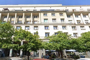 A multi-story building with balconies, a courtyard with trees, and outdoor seating. - Elegant Apartment near Vitsula River (Warszawa)