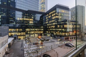 Ein modernes Gebäude mit mehreren Stockwerken, großen Glasfenstern und einem Parkplatz mit Autos.