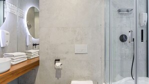 Une salle de bain moderne avec une douche à parois de verre, un meuble-lavabo en bois et des toilettes.