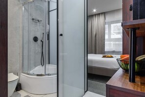 A modern bathroom with a glass-enclosed shower, a toilet, and a bed with a breakfast tray. - Modern Romantic CIty Getaway (Warszawa)