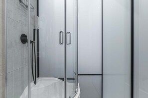 Eine moderne Duschkabine mit Glastür, Handbrause und Bedienfeld.