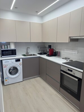 A modern kitchen with a built-in washer, a microwave, a coffee machine, and a stove. - Trinity Breeze, Lovely Renovated 2 bedroom apt Near the Beach & Private Parking (Paralimni)