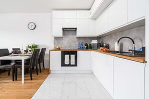 Eine moderne Küche mit weißen Schränken, einer Holz Arbeitsplatte und einem eingebauten Ofen.