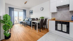 A modern apartment with a dining area, kitchen, and a balcony with a view. - Beautiful Seaview Flat in Stagadon Island (Łódź)