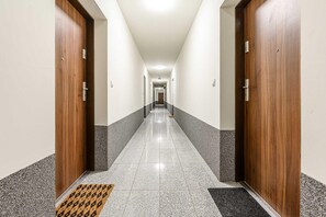 Ein Hotel-Flur mit Holztüren, Fliesenboden und Fußmatte am Eingang.