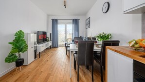A modern kitchen with a dining area, a TV, and a large window. - Beautiful Seaview Flat in Stagadon Island (Łódź)