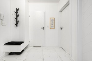A minimalist bathroom with a white sink, a black countertop, and a white tiled floor. - Beautiful Łódź Apartment for 6 Guests (Łódź)