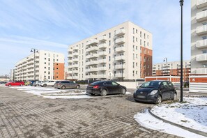 A parking lot with several cars and a multi-story residential building in the background. - Beautiful Łódź Apartment for 6 Guests (Łódź)