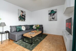A modern living room with a grey sofa, a wooden coffee table, and a green rug. There are two paintings on the wall, a lamp, and a TV. - Charming Warsaw Apartment for 6 (Warszawa 2)