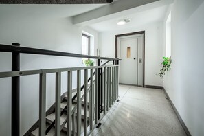 Ein Flur mit Metallgeländer, einer Tür und einem Blumentopf.